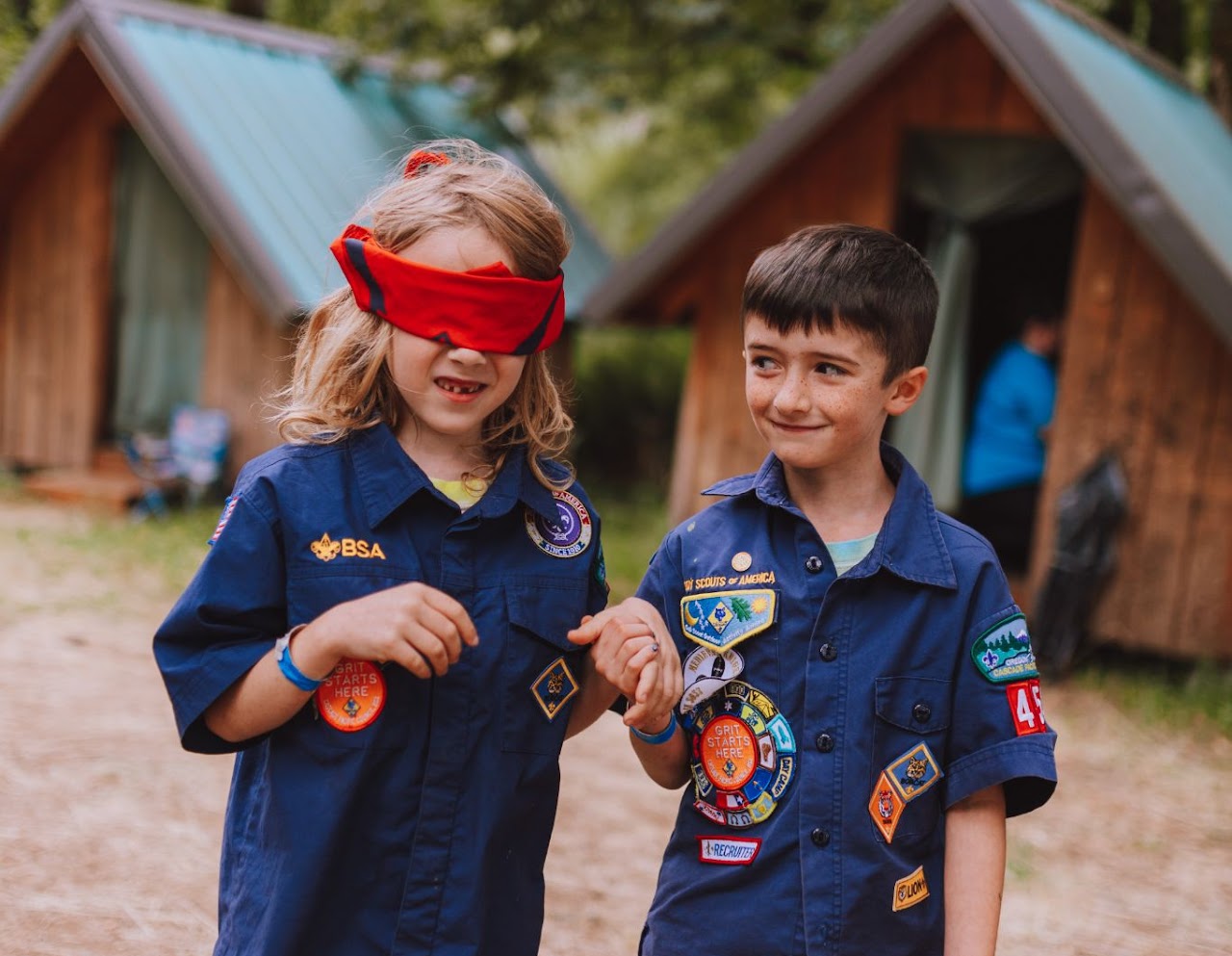 Two Pack 454 Cub Scouts in uniform standing together at summer camp, one wearing a red bandana