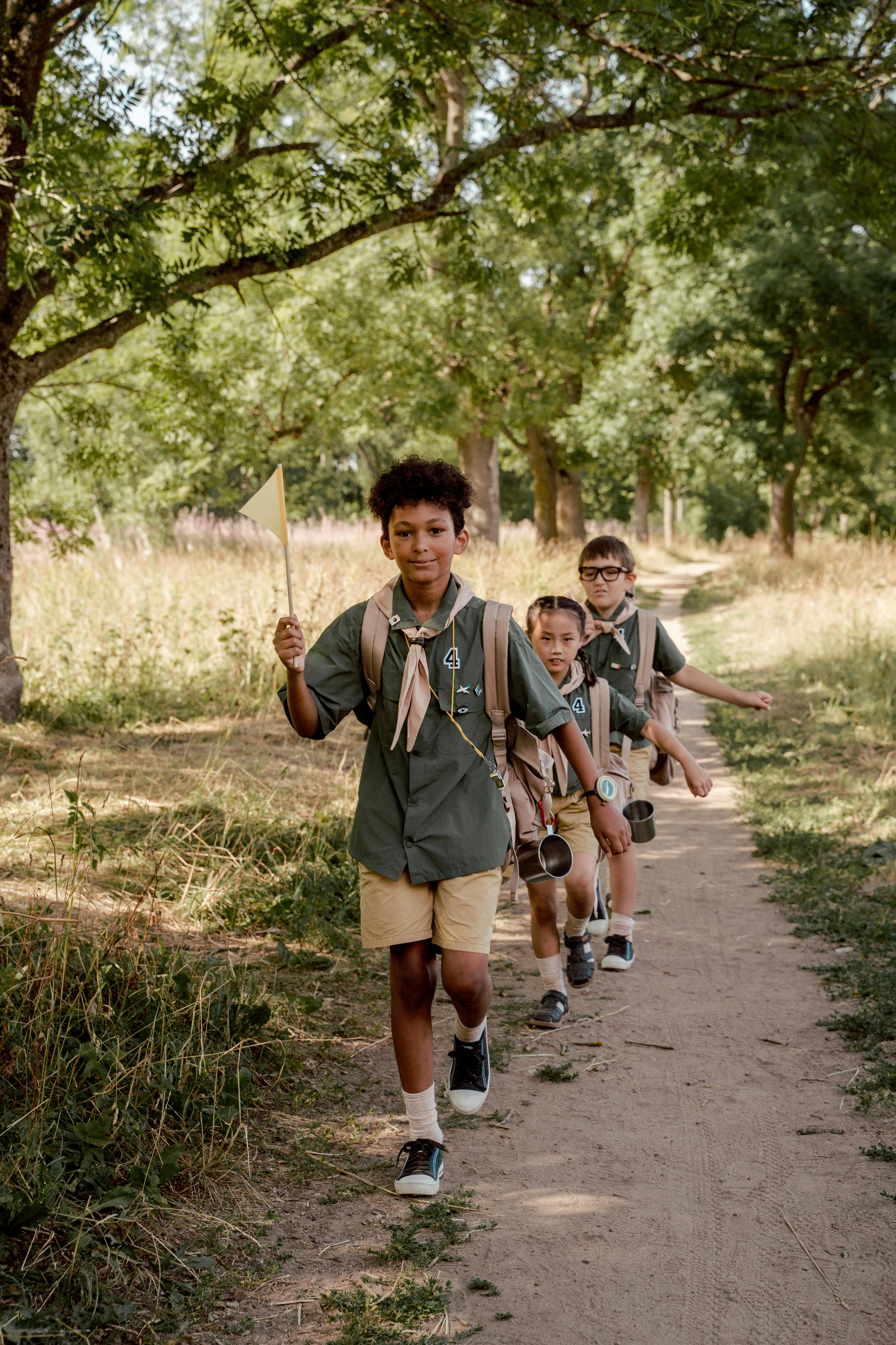 Cub Scouts in uniform hiking a forest trail together